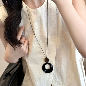 Close-up of a hollow resin circle pendant on a minimalist long necklace worn by a model