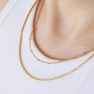 Close-up of double layered gold chains featuring a twisted rope and bead necklace