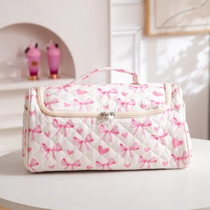 Quilted white cosmetic bag with pink bow patterns and a sturdy top handle detail