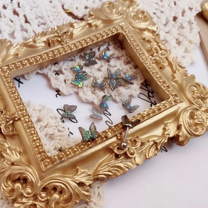 Close-up of iridescent butterfly stud earring on vintage gold frame and white lace