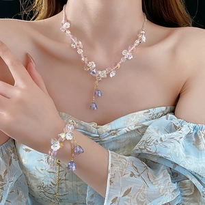 Detail of pink crystal beaded necklace and bracelet set with floral and bow accents