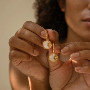 Pendientes vintage sol de oro 18K con nácar blanco, mostrados en la mano