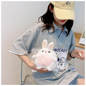 Detail of white plush rabbit crossbody bag with golden chain strap worn by a model