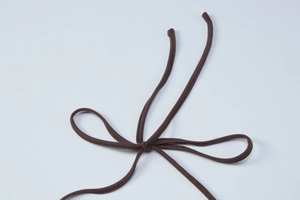 Detail shot of the dark brown adjustable spaghetti strap knot on a knitted dress