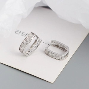 Macro detail of S925 silver U-shape earrings with zircon micro-paving and floral cutout pattern