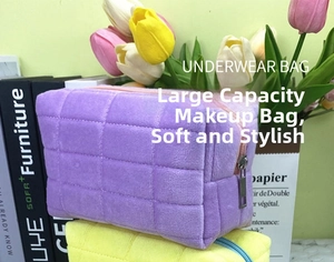 Close-up of checkered plush stationery pouch in purple and yellow with metal zipper