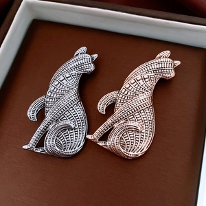 Detail of cat brooches in silver and rose gold with geometric textured engraving