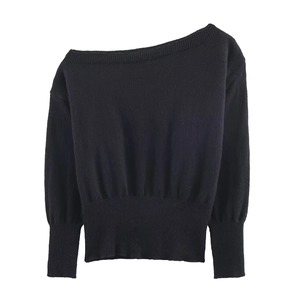 Detail of off-shoulder black knit sweater showing ribbed hem and lantern sleeve texture