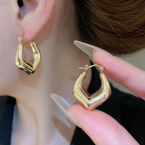 Detailed close-up of golden geometric U-shaped earrings with a polished metallic finish