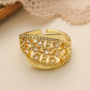 Gold hollow floral open ring with white zircons on a warm beige background