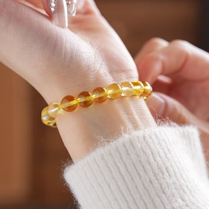 Close-up of yellow citrine bead bracelet on woman's wrist with elegant knitwear sleeve