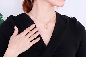 Gros plan d'un collier doré en acier inoxydable avec pendentif rond lettre T
