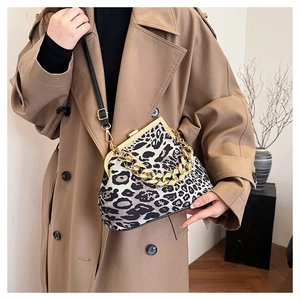 Close-up of leopard print handbag with gold chain handle on khaki trench coat