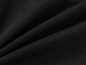 Vue macro de la maille fine et du drapé de ce haut noir moulant à épaules dénudées