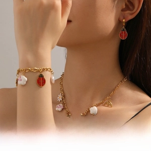 Detail of ladybug and floral gold-tone jewelry set on model including necklace and bracelet