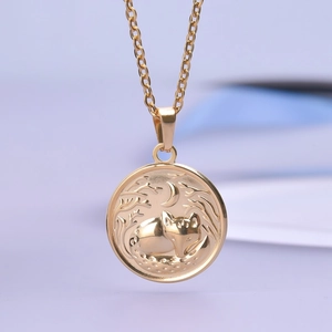 Macro shot of gold-plated pendant featuring a detailed fox and crescent moon engraving