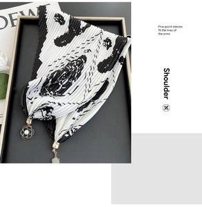 Detail of pleated scarf with black and white print and metal camellia pearl pendant