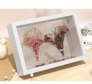 Detailed shadow box frame with preserved red and pink dried flowers on a wooden table