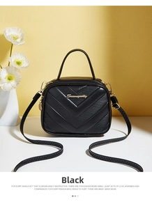 Detail of black V-quilted crossbody bag with gold hardware and top handle on table