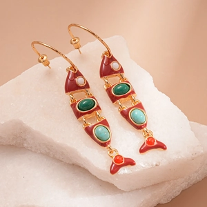 Detailed macro shot of vintage gold fish tassel earrings with red enamel and colorful gems