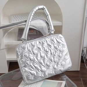 Silver quilted laptop sleeve with bow stitching and padded handles in office setting