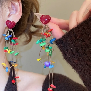 Macro shot of silver needle heart earrings with colorful beaded tassel details