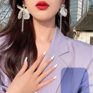 Détail de boucles d'oreilles nœud en tissu avec glands de perles portées par un mannequin