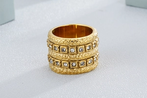 Detailed macro view of gold-plated wide ring with hammered texture and two rows of cubic zirconia