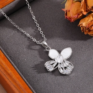 Detailed view of silver bow necklace with white shell inlay and heart-shaped zircon