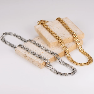 Classic silver and gold 11mm curb chain necklaces displayed on minimalist beige stones