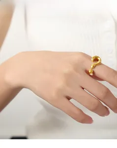 Macro detail of a minimalist gold-plated stainless steel ring in a unique question mark shape