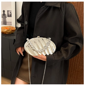Detail of silver shell-shaped evening bag with pleated texture and beaded handle