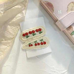Detail of sweet cherry embroidery hair clips with wavy lace edges on a display card