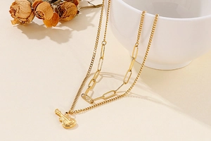 Detail of layered gold guitar necklace with double chains on a minimalist background