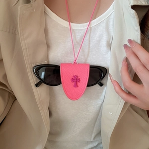 Detail of pink pebbled leather eyewear holder necklace with cross motif on white shirt