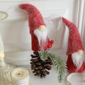 Christmas gnome ornaments with red felt hats and natural pine cones on a fireplace mantel