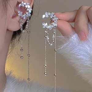 Détail d'un ear cuff argenté orné de fleurs en zircone et de fines chaînes pendantes