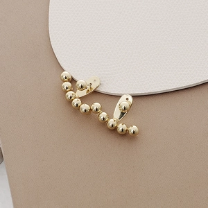 Detail view of gold beaded curved earrings featuring a minimalist polished sphere design