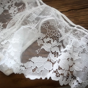 Dettaglio in pizzo floreale bianco con maglia traspirante su sfondo di legno