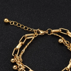 Macro detail of 18k gold-plated layered chain bracelet with lobster clasp and extender