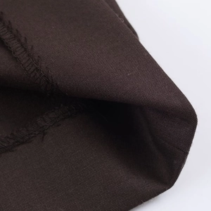 Détail du tissu en coton marron foncé montrant le tissage fin et la qualité des coutures