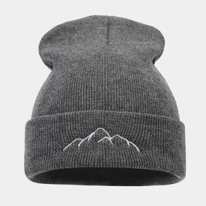 Macro detail of mountain peak embroidery on a thick dark gray knitted beanie hat