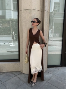 Detail of slim fit dark brown sleeveless knit cardigan with side slit and lace midi skirt
