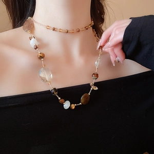 Dettaglio della collana di perline a strati con cristalli color ambra, bianco e marrone