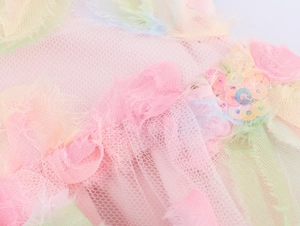 Detailed macro view of pink mesh fabric with iridescent sequins and colorful feather trim