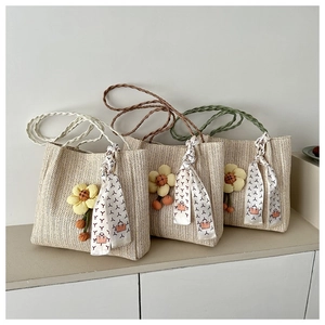 Three woven bucket bags with colorful straps and yellow floral charms in a minimalist setting