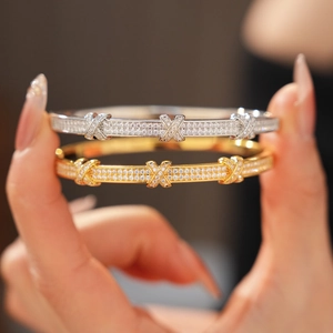 Macro detail of 18k gold plated X-shaped bangle with pave set sparkling zircons