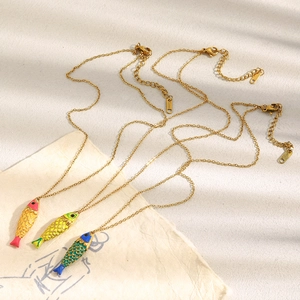 Macro detail of 18K gold plated fish pendants with vibrant colorful enamel texture
