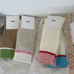 Close-up of knit cotton socks with ruffle trim and heart pattern on lace background