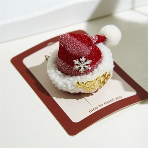 Close-up of glittery red Christmas hat hair clip with plush trim and Merry lettering